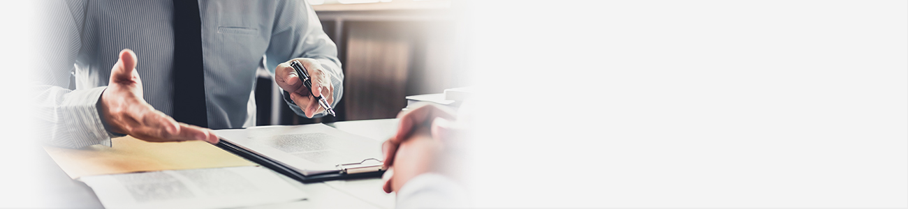 Two men converse at a desk,